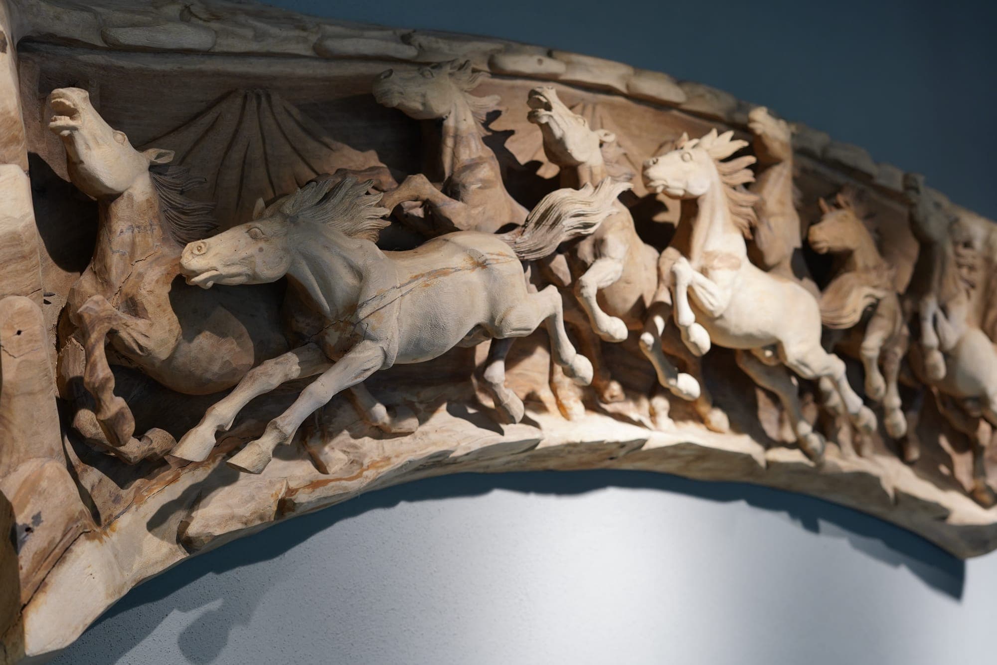 A carved stone relief of galloping horses mounted on the office wall
