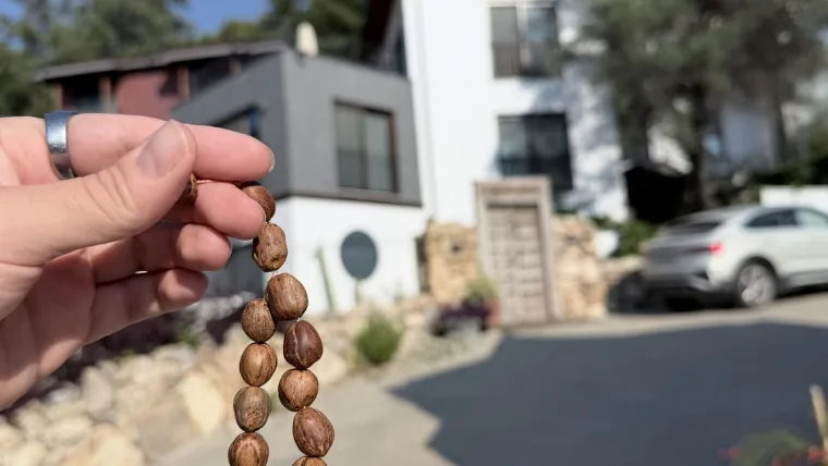 A hand holding the one-dollar kuka tesbih prayer beads on a sunny street